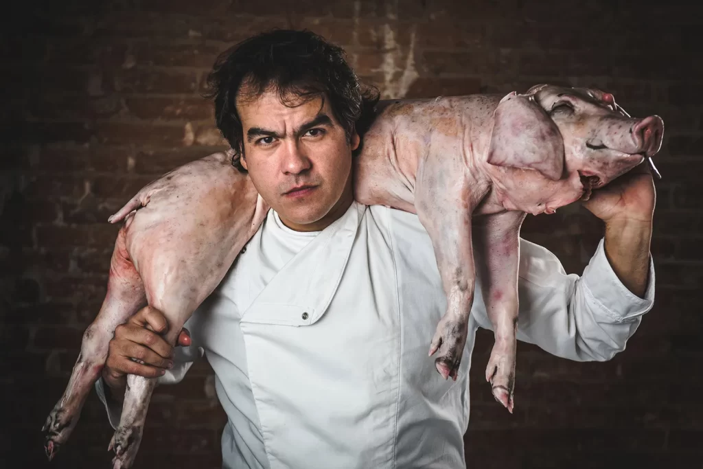 Professional photographer in London – promotional portrait of a restaurant chef holding a raw pig by Rafael Bastos Photography.